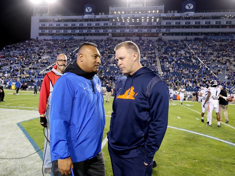 Virginia Cavaliers head coach Bronco Mendenhall and Brigham Young Cougars head coach Kalani Sitake talk at midfield.