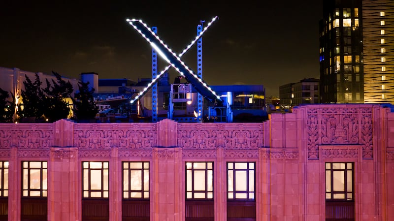 Workers install lighting on an “X” sign atop the company headquarters, formerly known as Twitter, in downtown San Francisco.