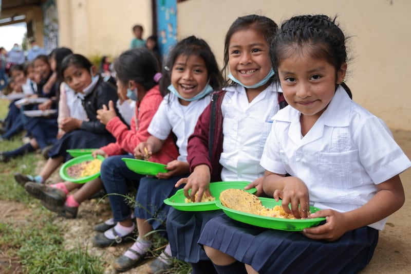 Madelyn Sofia Mendez Mateo (far right), a first-grade student in Honduras, eats a meal during recess time with her classmates.