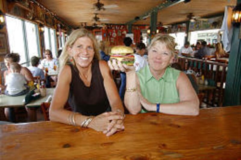 Cheeseburger In Paradise founders Edna Bayliff, left, and Laren Gartner show a trademark burger at their Lahaina restaurant.