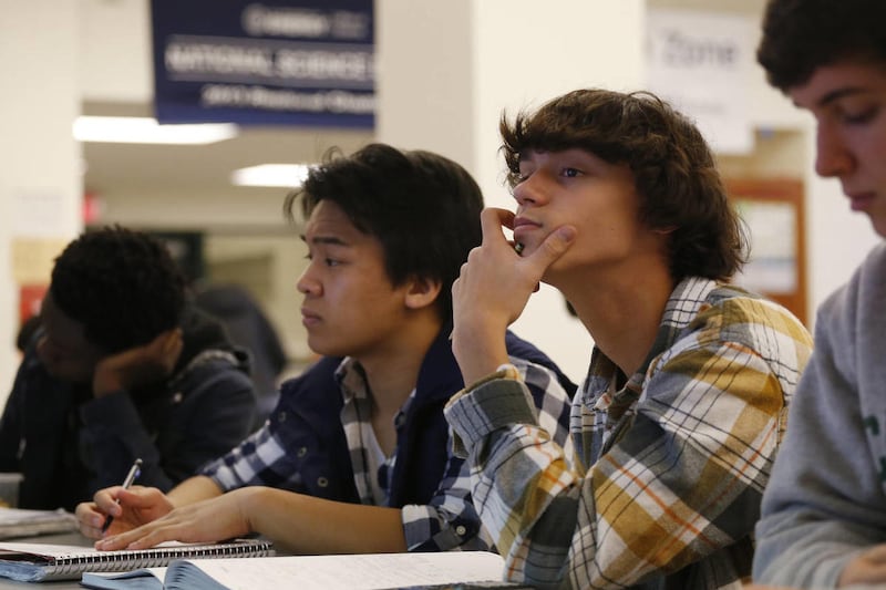 Students Julian Lopez, 12th grade, second left; Ben Montalbano, 11th grade, second right; and James Agostino, 12th grade, right; listen during their Advanced Placement Physics class at Woodrow Wilson High School in Washington, Friday, Feb. 7, 2014. A new,