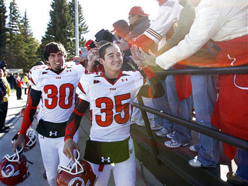 The University of Utah's All-American punter and place kicker Louie Sakoda (35) and K/P Ben Vroman (30) "high-five" with the fans as they leave the field after the Utes' 40-7 win over the Cowboys.