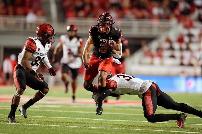 Micah Bernard, wearing black, of the Utah Utes runs the ball for a first down