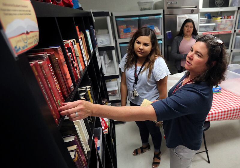 Librarian Julie Anzelmo, right, Karina Soto, family services assistant, restocks books that students can take at the Smith's East High Leopard Stash at East High School in Salt Lake City on Tuesday, June 18, 2019.