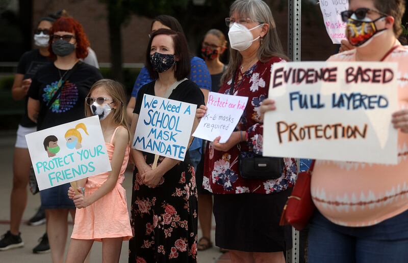 Torah Neil, 10, third from left, holds a sign in support of school mask mandates.