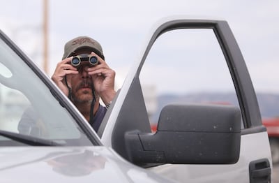 Doug Adams uses binoculars to look for his house from the parking lot of and LDS church in Fruitland on Wednesday, July 11, 2018. Adams' house was destroyed in the Dollar Ridge Fire.