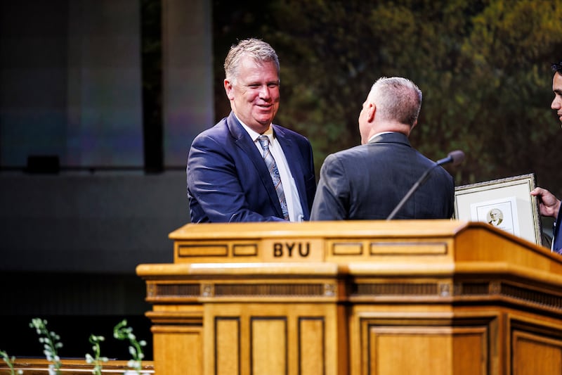 Curt Holman, accepts the 2025 Karl G. Maeser Distinguished Faculty Lecturer Award from BYU President Shane Reese.