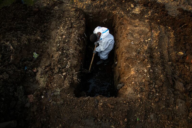 A man in protective suit digs earth to bury the body of a person who died of COVID-19 in Gauhati, India.