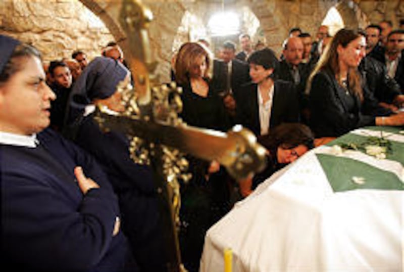 Nicole Gemayel, center, sister of prominent anti-Syrian Christian politician Pierre Gemayel, sits and mourns with other friends and relatives at her brother's coffin, draped in the flag of his Phalange Party, at his family home in Bikfaya, Lebanon, Wednes