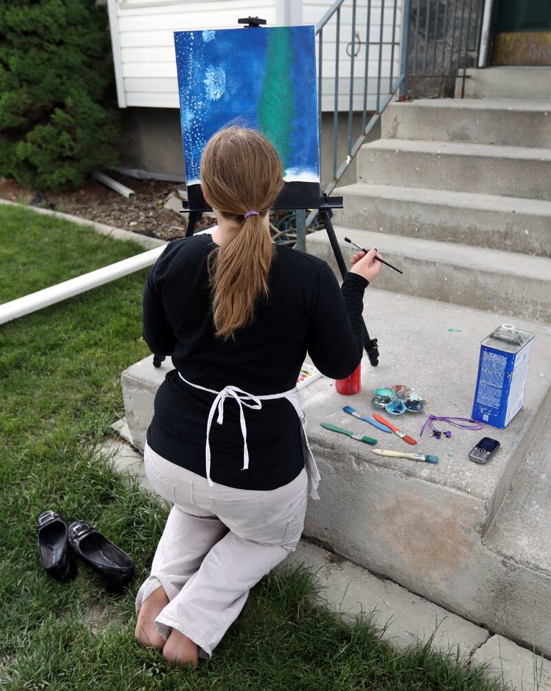 Christine, who struggles with anxiety, paints outside of her home in Murray on Friday, May 18, 2018. Painting helps her express her emotions.