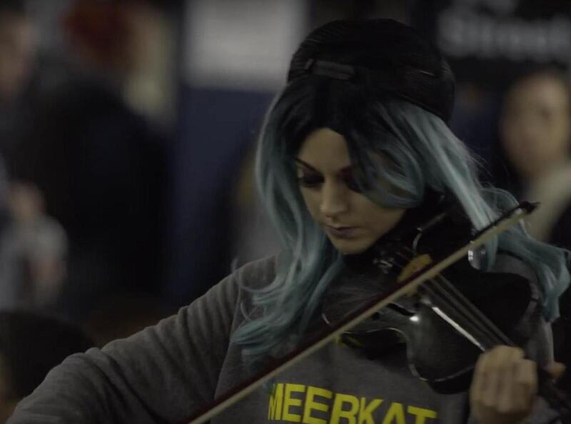 Lindsey Stirling is shown in disguise performing in a subway station.