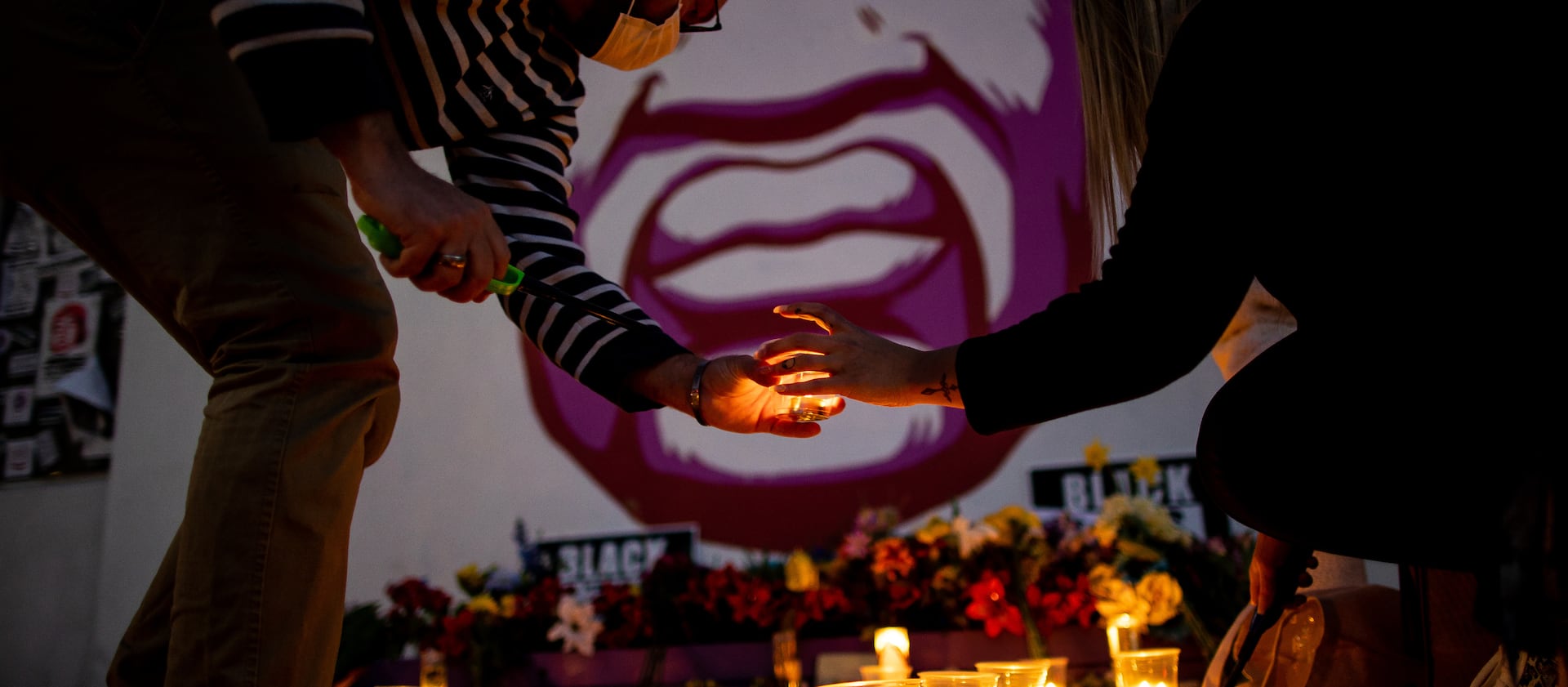 Rob Hall and Misti Western light candles in front of a mural of George Floyd in Salt Lake City.