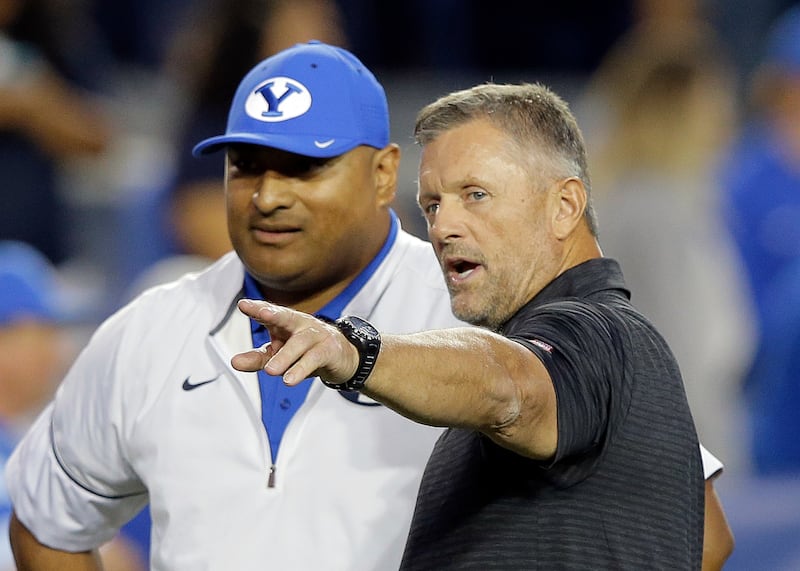 Utah coach Kyle Whittingham, right, and BYU coach Kalani Sitake speak before a game Saturday, Sept. 9, 2017, in Provo, Utah.