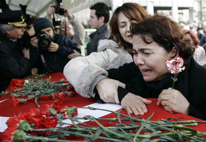 Relatives of pilot Hasan Tahsin Arisan mourn over his coffin during a ceremony outside the Turkish Airlines headquarters in Istanbul Saturday.