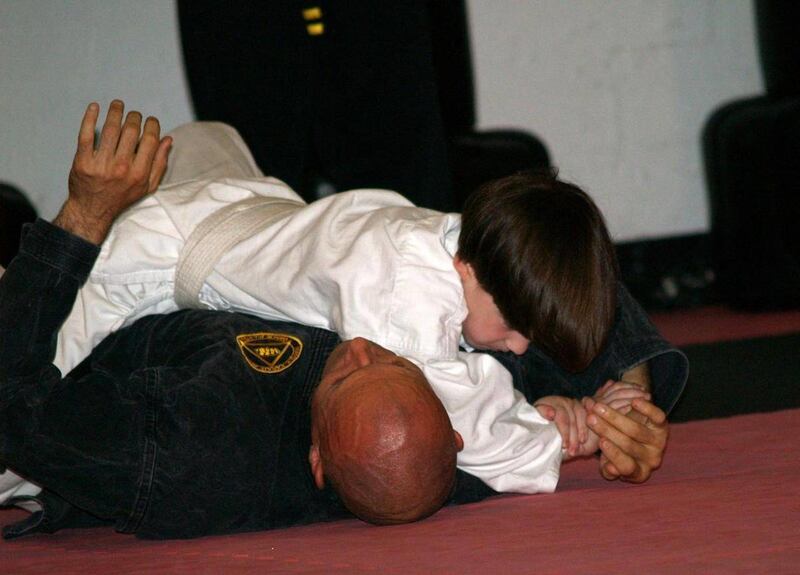 This June 2010 photo provided by Lisa Suhay shows her son Quin Suhay, now 8, tackling Bill Odom, owner of Norfolk Karate Academy in Norfolk, Va., as part of a bullyproofing class that combines jujitsu _ defensive moves only, no punching or kicking _ with
