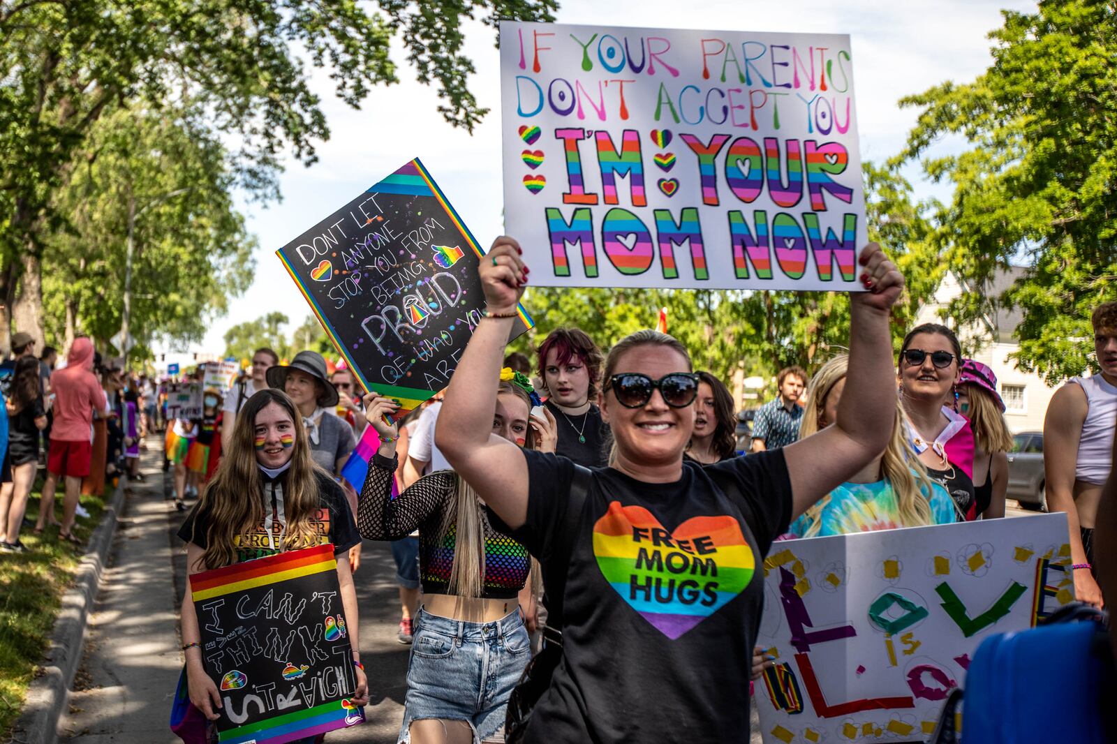 Individuals hold up signs during the Rainbow March along State Street and 900 South headed to Liberty Park in Salt Lake City on Sunday, June 6, 2021.