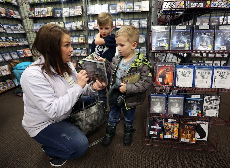 Robyn Christensen shows some video options to her sons Ryker, 8, and Brody, 4, before choosing one to rent at Top Hat Video in Bountiful on Friday, Jan. 26, 2018.