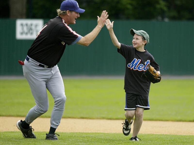 Former major league player Steve Lyons high-fives 11-year-old Zachary D'Errico after D'Errico makes a double play.