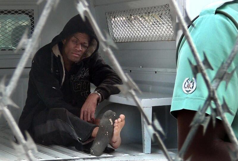 American citizen Marcus Kevin Tomas, sits inside a police van in Windhoek, Namibia, Monday, Nov. 3, 2014. Tomas, on Sunday climbed a tree inside the Windhoek Central Prison and tried to jump over the barbed wire fence but instead landed on top of the fenc