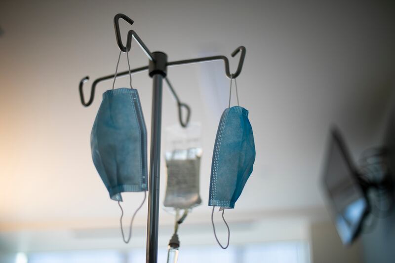 A patient receives an IV drip as face masks hang from an IV pole at a hospital in Portland, Ore., on Saturday, Aug. 8, 2020. Nurses and doctors in Oregon say they are finding little relief with coronavirus infections spreading at record levels, taxing the capacity of many hospitals.