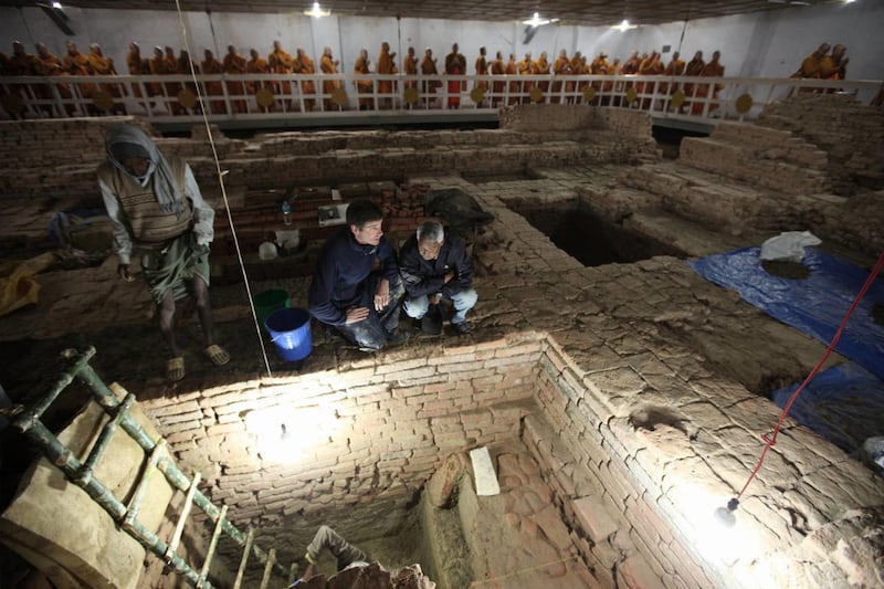 In this undated but recent photo released by National Geographic, archaeologists Robin Coningham, second from right, of Britain's Durham University and Nepalese archaeologist Kosh Prasad Acharya, right, direct excavations within the Mayadevi Temple, uncov