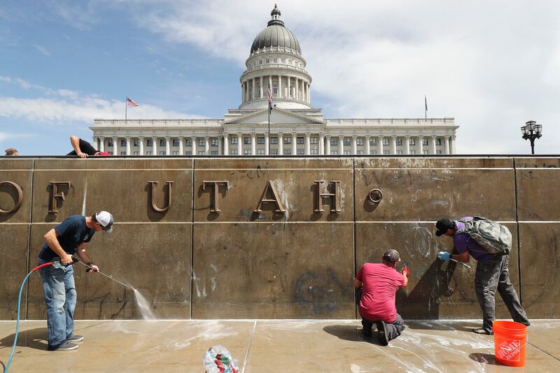 Workers scrub graffiti on the Capitol grounds in Salt Lake City on Sunday, May 31, 2020. Daylong protests moved across the city Saturday after a peaceful demonstration to decry the death of George Floyd in police custody in Minneapolis turned violent. Protesters vandalized buildings throughout the downtown area before a curfew was enforced in the evening.