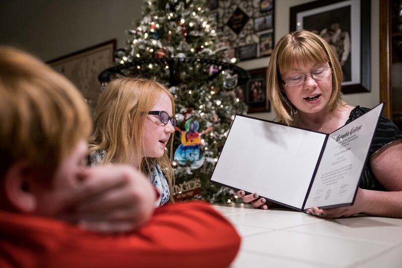 Veronica Banton holds her college diploma as her daughter, Sara, reads it out loud with her son, Chris looking on, at their home Thursday, Nov. 15, 2018 in Lexington, S.C.