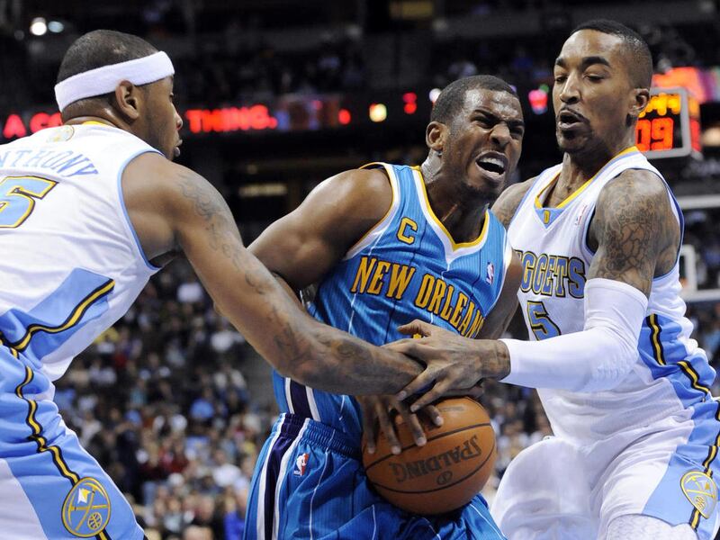 Denver Nuggets forward Carmelo Anthony (15) and J.R. Smith (5) get a hand on the ball as New Orleans Hornets guard Chris Paul (3) drives to the basket during the first half of an NBA basketball game Sunday, Jan. 9, 2011, in Denver.