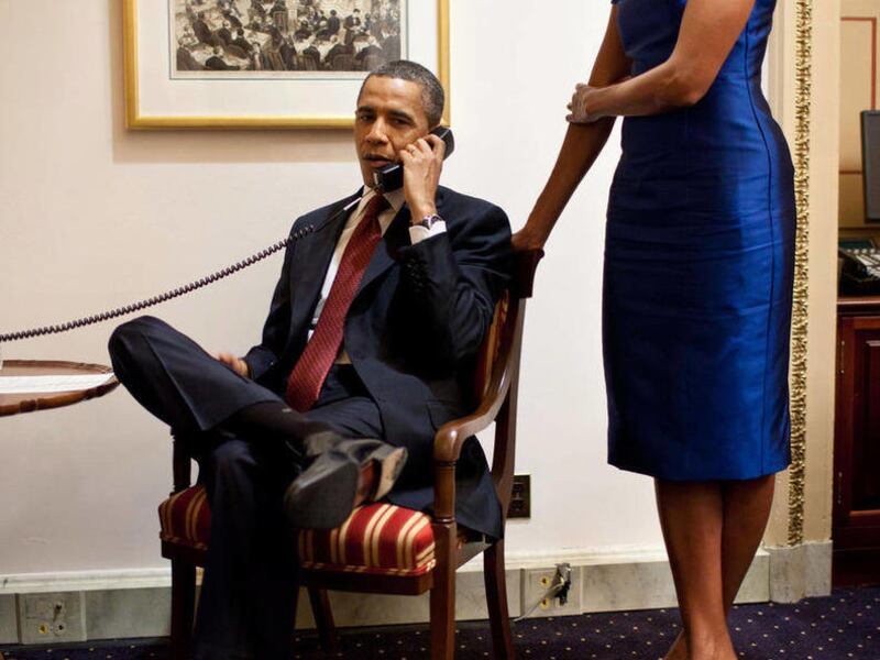 This handout photo provided by the White House shows President Barack Obama, accompanied by first lady Michelle Obama, during a phone call from the Capitol in Washington, Tuesday, Jan. 24, 2012, immediately after his State of the Union Address, informing