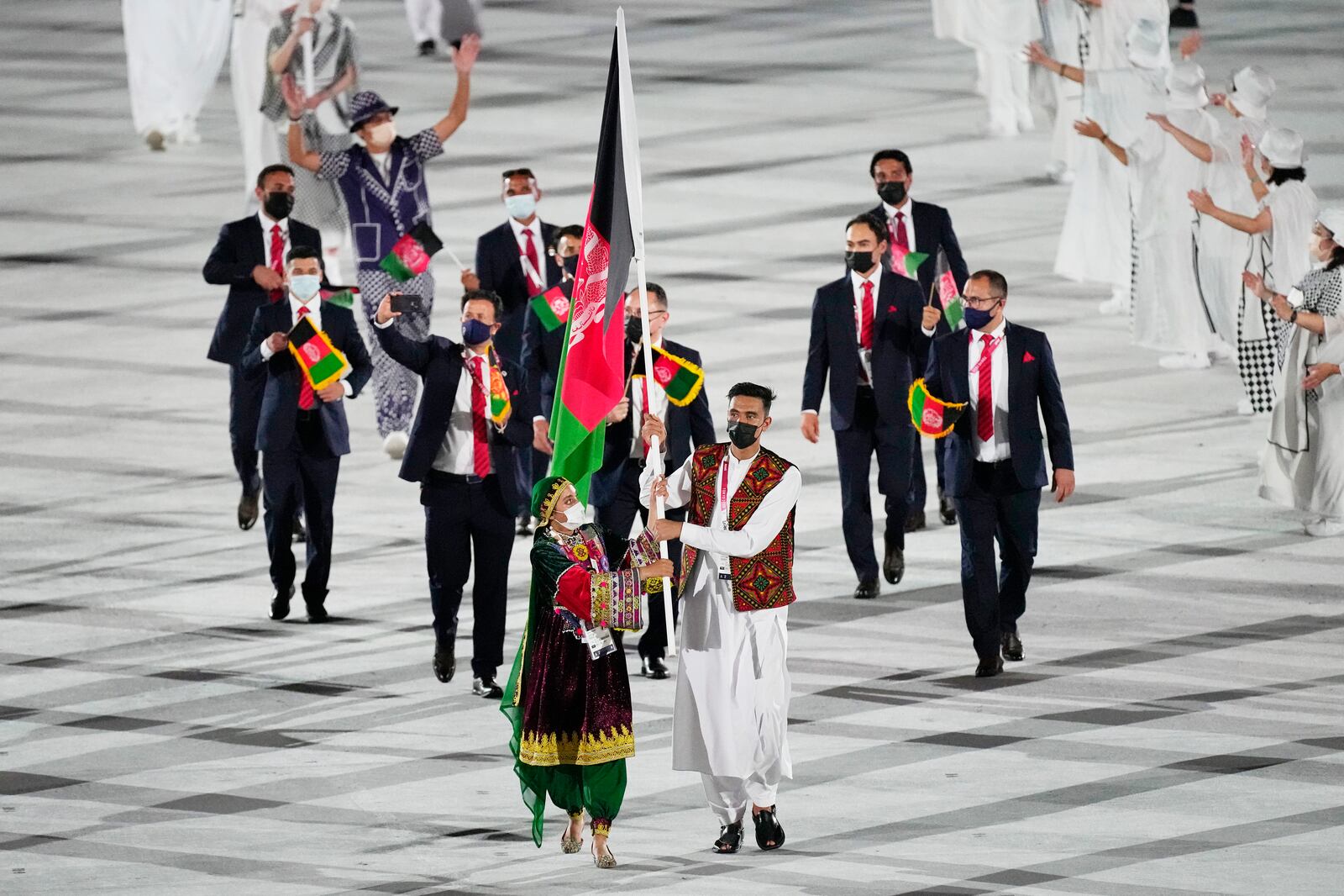 Kimia Yousofi and Farzad Mansouri, of Afghanistan, carry their country’s flag at the 2020 Summer Games’ opening ceremony.