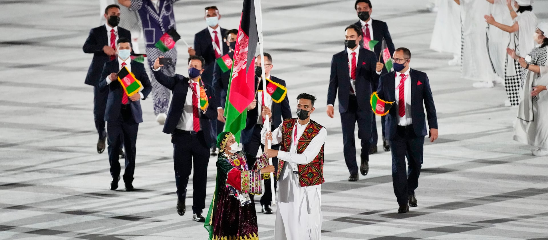 Kimia Yousofi and Farzad Mansouri, of Afghanistan, carry their country’s flag at the 2020 Summer Games’ opening ceremony.