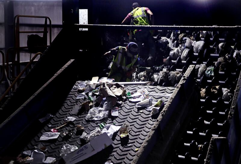In this Thursday, Sept. 6, 2018, photo, workers clean consumer plastic shopping bags from the clogged rollers of a machine which separates paper, plastic and metal recyclable material, in a processing building at EL Harvey & Sons, a waste and recycling co