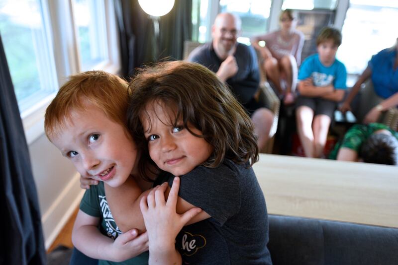 Siblings Nate and Winnie Buck, 4 and 5, hug as mom, Melissa, dad, Chad, and siblings look on at their home in Holt, Michigan. The Bucks adopted their children through St. Vincent Catholic Charities of Michigan, which is involved in a lawsuit over whether