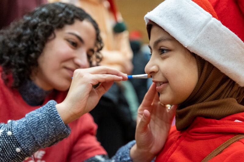 Samar Al Ibrahim paints the face of Zahraa Neamh, 9, at the Utah Refugee Connection “Celebration of Light” in South Salt Lake.