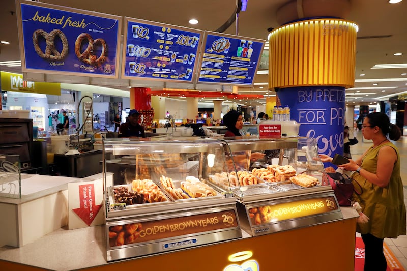 In this Oct. 18, 2016 photo, a customer purchases a pretzel at Auntie Anne’s at a shopping mall in Kuala Lumpur, Malaysia.