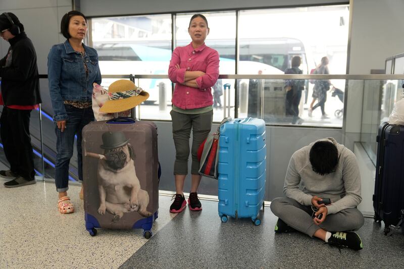 Travelers from Hong Kong wait for travel options after their vacation flight to Cancun, Mexico, was suddenly canceled disrupting their planned vacation at the United Airlines terminal at Los Angeles International airport in Los Angeles.