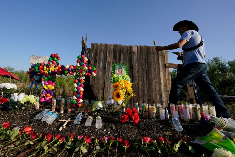 Roberto Marquez, of Dallas, adds a flower to a makeshift memorial where officials found dozens of people dead in a semitrailer.