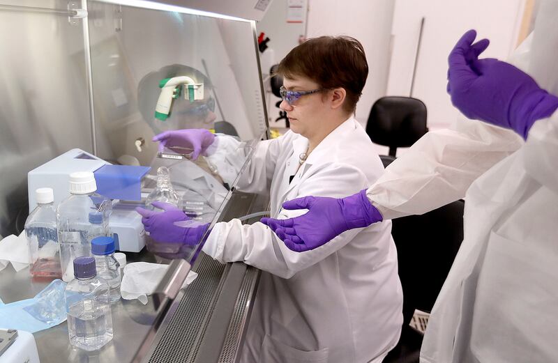 Lawrie Allred, HTS engineer, hands a cell plate to a coworker while seeding cells at Recursion Pharmaceuticals, at The Gateway in Salt Lake City on Tuesday, Oct. 30, 2018.
