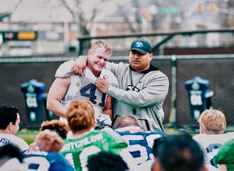 Adam Pulsipher interacts with coach Kalani Sitake at a practice.