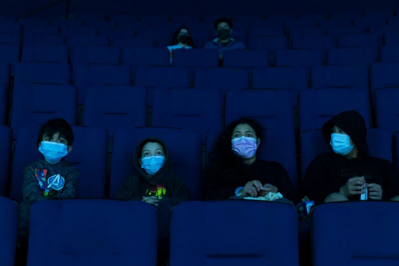 Visitors wear face masks while watching a presentation in a theater at the Aquarium of the Pacific on its first day of reopening to public in Long Beach, Calif., Tuesday, March 16, 2021. California has been on a reopening roll since a deadly winter surge that saw skyrocketing hospitalizations and positivity rates