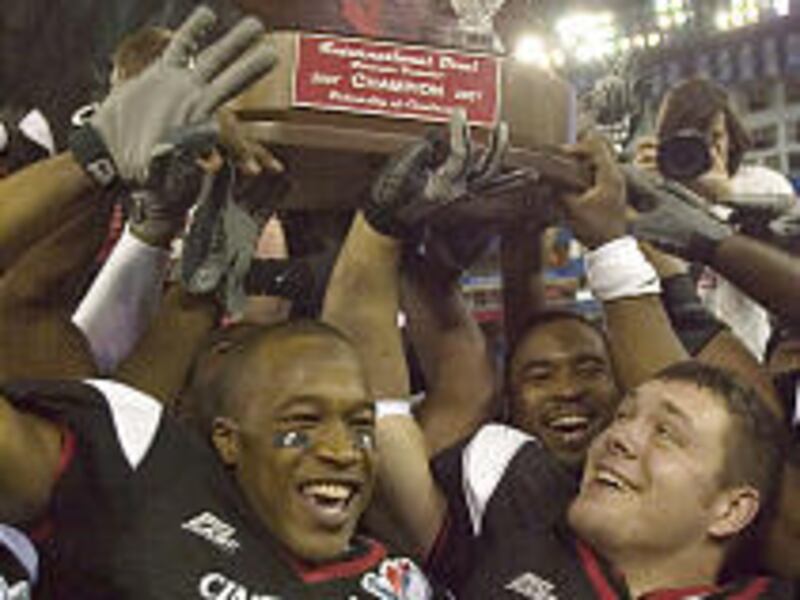 Cincinnati's Antwuan Giddens, left, and Marcus Weigh celebrate as the team hoists the inaugural NCAA International Bowl trophy.