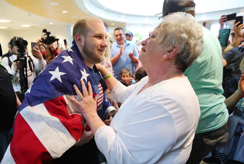 Josh Holt's grandmother Linda Holt drapes an American flag around him as he and his wife Thamy are swarmed by family and friends at the International Terminal in Salt Lake City International Airport on Monday, May 28, 2018.