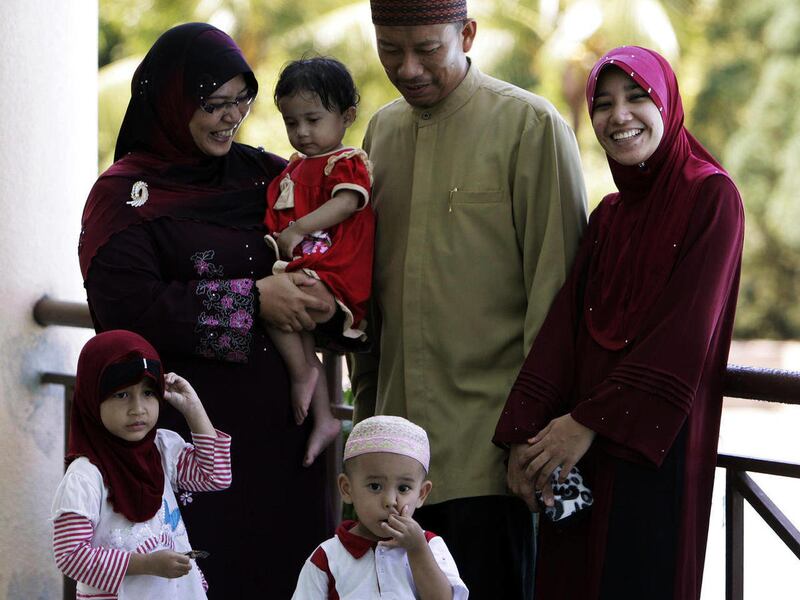 FILE - In this Saturday, June 4, 2011 file photo, Malaysian Muslim Ishak Md Nor, 40, second from right, and his two wives, Aishah Abdul Ghafar, 40, left, and Afiratul Abidah Mohd Hanan, 25, who are members of the Obedient Wives Club, pose with their child