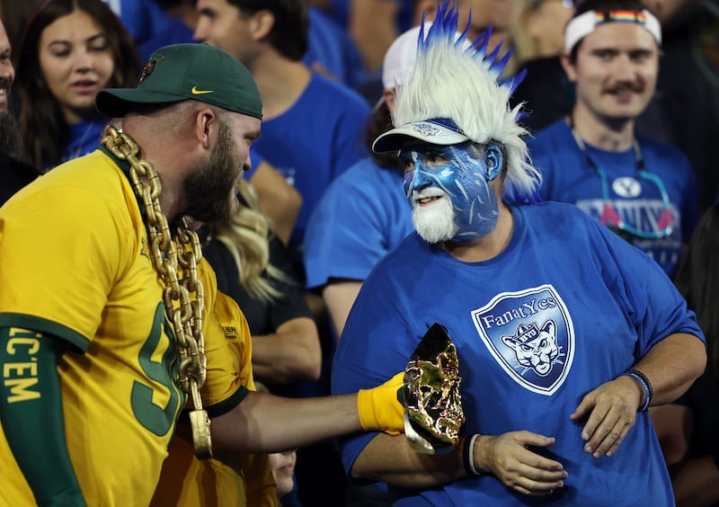 A Baylor fan and a BYU fan talk after BYU scored a touchdown at the end of the first half at LaVell Edwards Stadium in Provo.