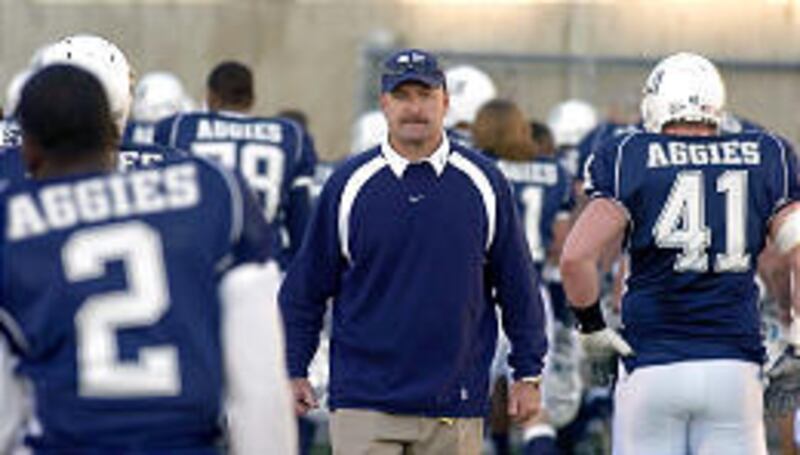 USU coach Brent Guy, center, watches the Aggies leave the field after capping a 1-11 campaign with a 42-20 loss to New Mexico State.