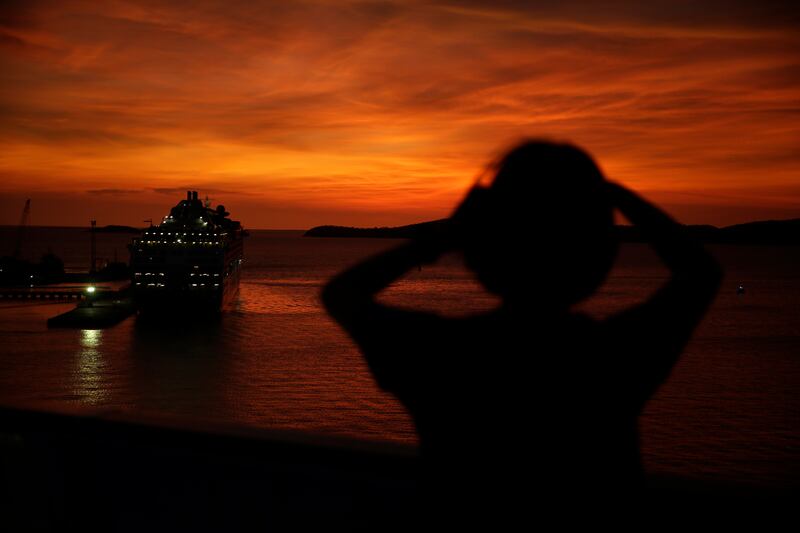 A visitor takes a photo of the P&O Pacific Explorer cruise ship, site of the APEC CEO Summit, as it is docked in Port Moresby, Papua New Guinea, Sunday, Nov. 18, 2018. An acrimonious meeting of world leaders in Papua New Guinea failed to agree Sunday on a final communique, highlighting widening divisions between global powers the U.S. and China.