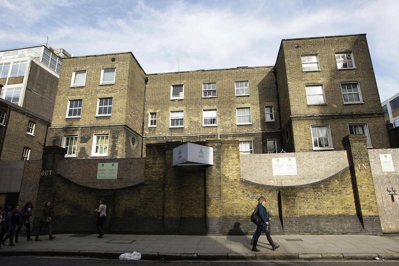 FILE - In this Thursday, Feb. 24, 2011 file photo, people walk by a dilapidated brick building in central London, where historians believe its neighbor and author Charles Dickens used the building, which was once a workhouse, as inspiration for his novel