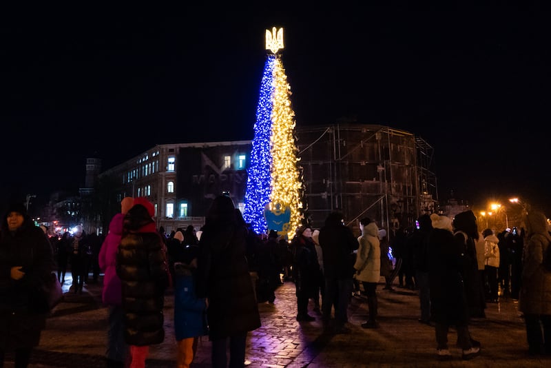 People attend the inauguration of a Christmas tree decorated with the colors of the Ukrainian national flag.