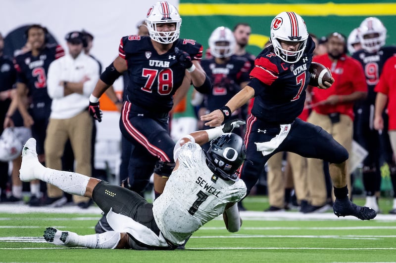 Utah quarterback Cam Rising evades the tackle of Oregon linebacker Noah Sewell during the Pac-12 championship game.