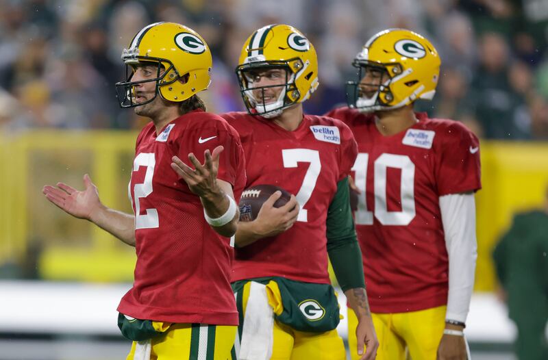 Green Bay Packers quarterback Aaron Rodgers (12) gestures to teammates while quarterbacks Kurt Benkert (7) and Jordan Love (10) look on.
